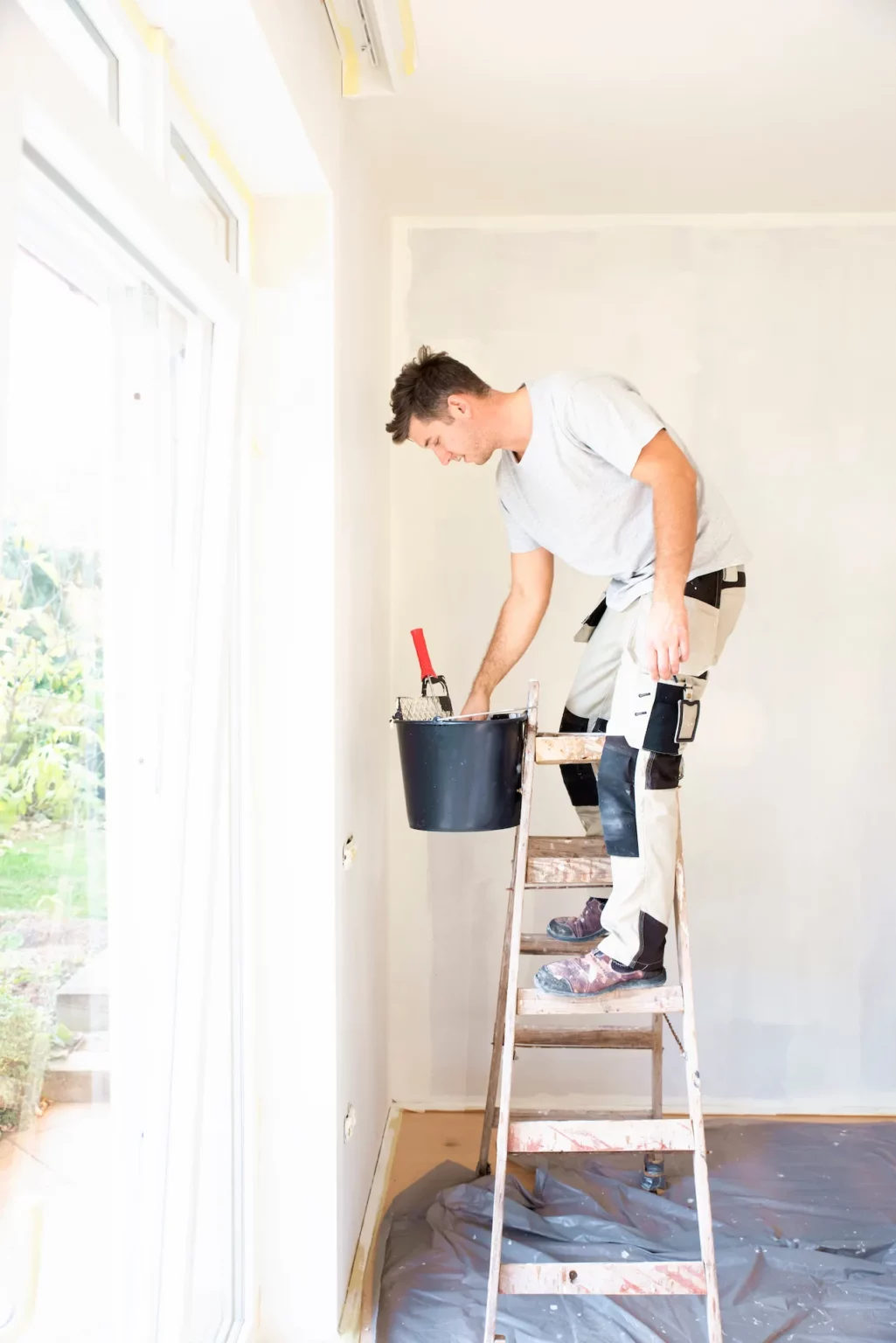 Photo d'un peintre en bâtiment sur une echelle
